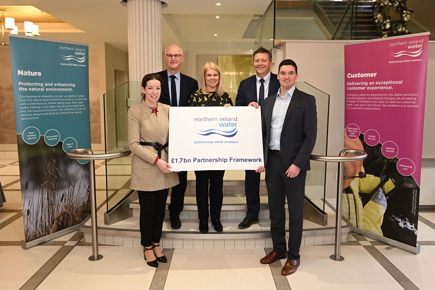 NI Water colleagues at Collaboration event standing at stairway holding banner